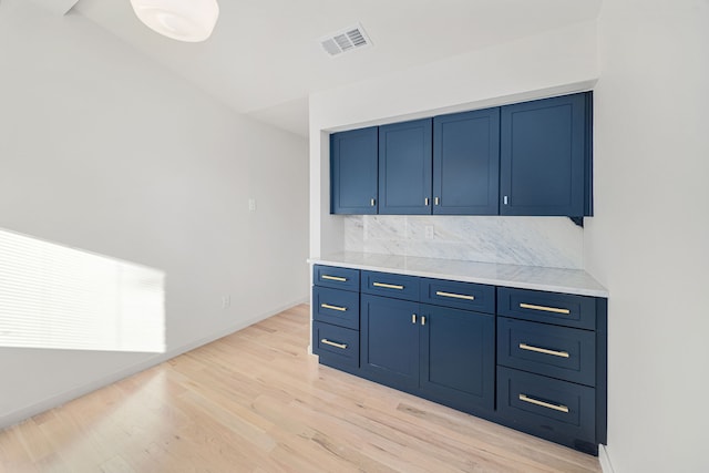 kitchen featuring decorative backsplash, light hardwood / wood-style floors, and blue cabinetry