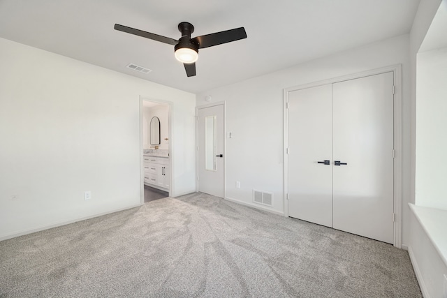 unfurnished bedroom featuring ceiling fan, a closet, light carpet, and ensuite bath