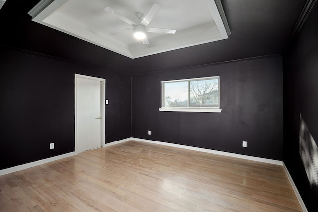 empty room with a tray ceiling, ceiling fan, and light hardwood / wood-style floors