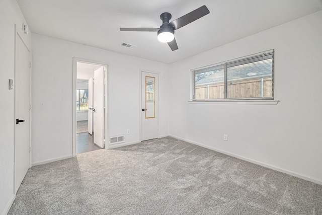 unfurnished bedroom with multiple windows, light colored carpet, and ceiling fan