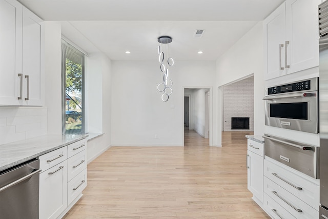 kitchen featuring white cabinetry, a fireplace, light stone countertops, and appliances with stainless steel finishes