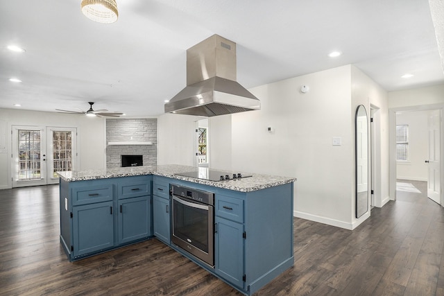 kitchen featuring dark wood-type flooring, blue cabinetry, black electric stovetop, island range hood, and stainless steel oven