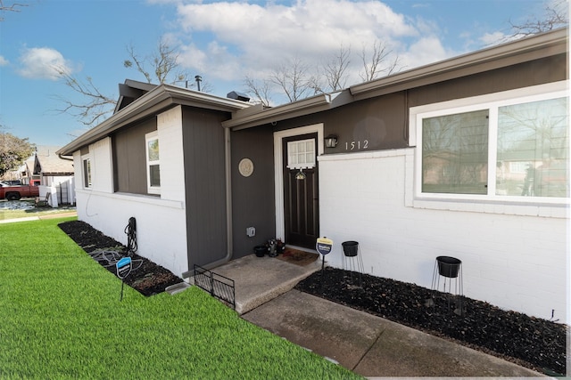 property entrance with a yard and brick siding