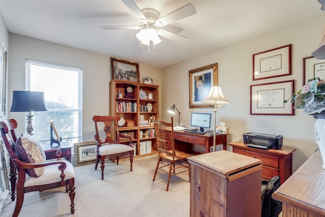 carpeted home office featuring a textured ceiling and ceiling fan