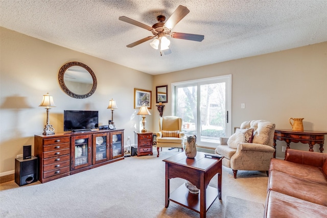 carpeted living room featuring ceiling fan and a textured ceiling