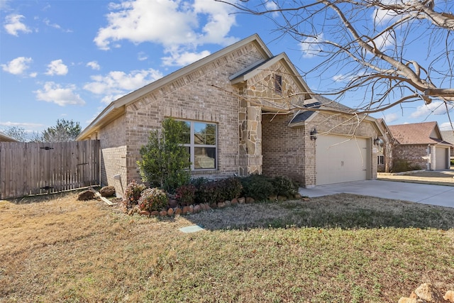 view of front of property with brick siding, fence, a front yard, a garage, and driveway