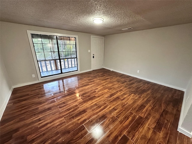 708 Ellington St, Atlanta, TX 75551 - unfurnished room with baseboards, visible vents, a textured ceiling, and dark wood-type flooring
