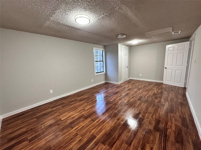 708 Ellington St, Atlanta, TX 75551 - empty room with attic access, a textured ceiling, baseboards, visible vents, and dark wood-type flooring