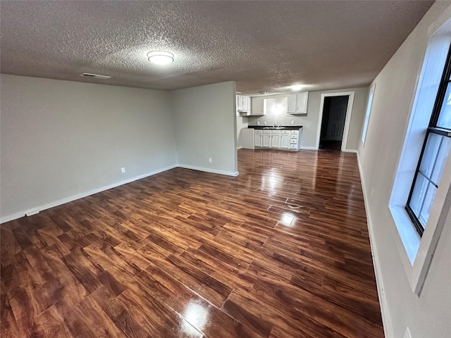 708 Ellington St, Atlanta, TX 75551 - unfurnished living room featuring baseboards, dark wood-style flooring, and a textured ceiling
