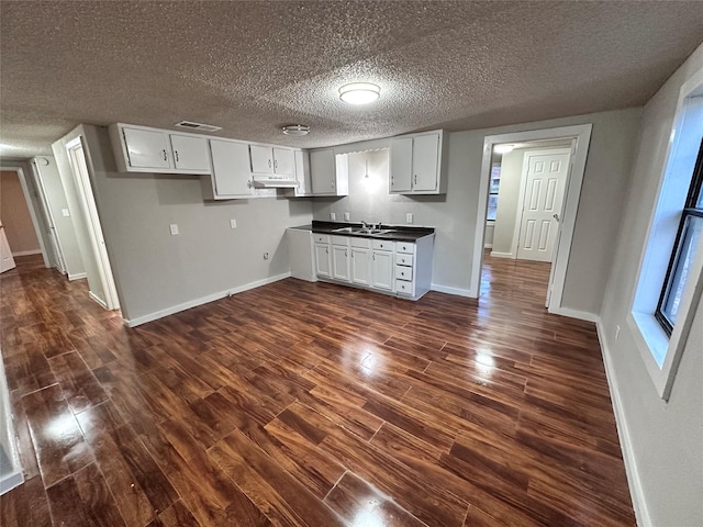 kitchen with dark hardwood / wood-style flooring, white cabinetry, sink, and a textured ceiling