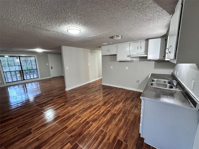 kitchen featuring white cabinets, a textured ceiling, dark wood-type flooring, and sink