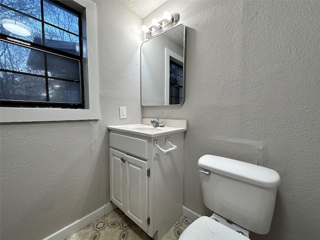 708 Ellington St, Atlanta, TX 75551 - bathroom with toilet, a textured wall, vanity, and baseboards