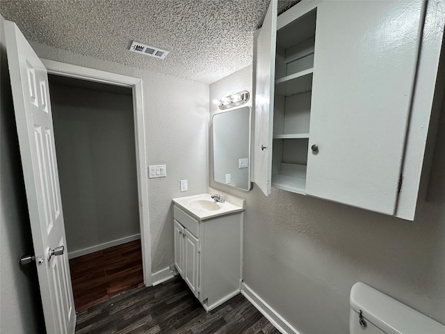 bathroom featuring vanity, a textured ceiling, hardwood / wood-style flooring, and toilet