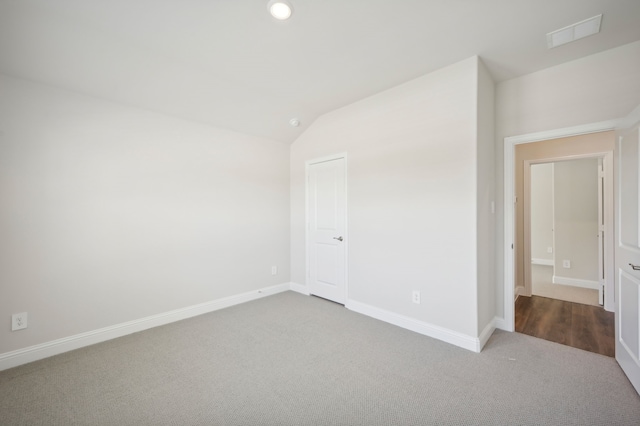 spare room with light colored carpet and vaulted ceiling