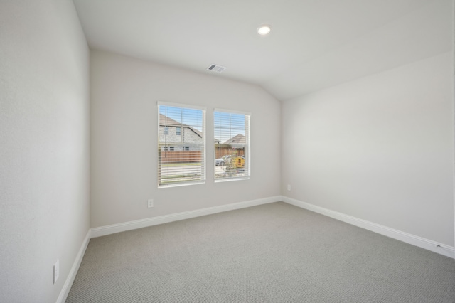 carpeted spare room featuring vaulted ceiling