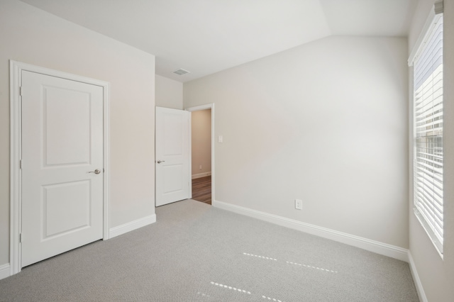 unfurnished bedroom featuring light colored carpet and vaulted ceiling