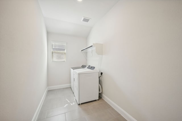 clothes washing area featuring light tile patterned floors and washing machine and clothes dryer