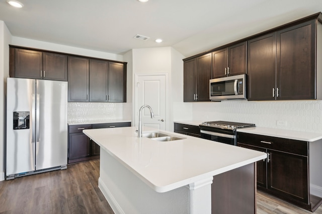 kitchen with an island with sink, stainless steel appliances, dark hardwood / wood-style floors, and sink