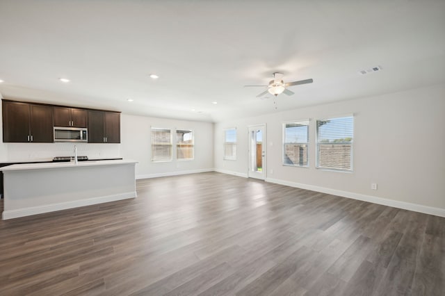 unfurnished living room featuring dark hardwood / wood-style floors, ceiling fan, a healthy amount of sunlight, and sink