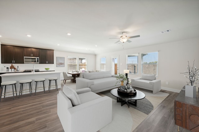 living room featuring ceiling fan, plenty of natural light, and dark wood-type flooring