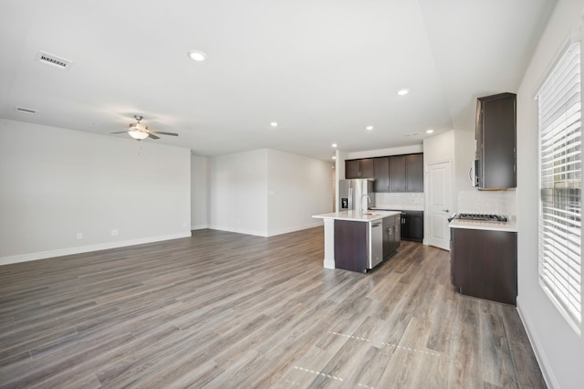 kitchen featuring backsplash, a wealth of natural light, a kitchen island with sink, and stainless steel appliances