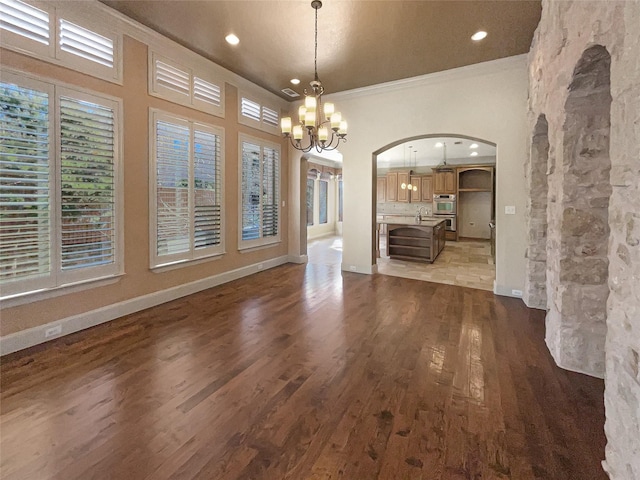 unfurnished dining area featuring ornamental molding, dark hardwood / wood-style flooring, and an inviting chandelier