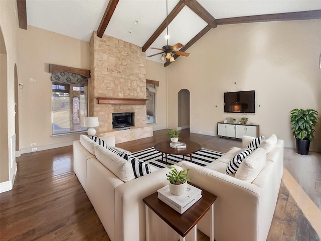 living room featuring hardwood / wood-style floors, high vaulted ceiling, beam ceiling, a fireplace, and ceiling fan