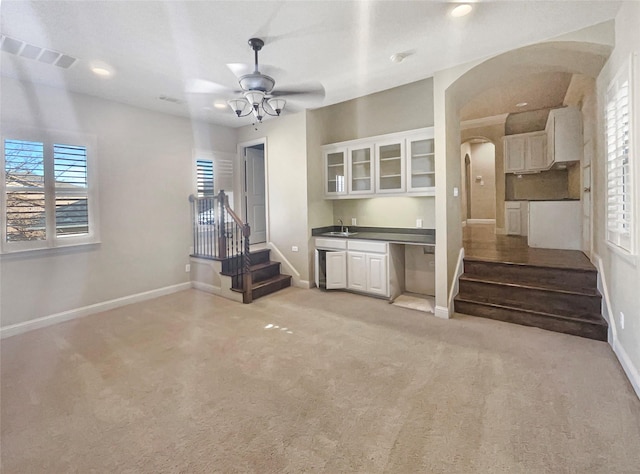 unfurnished living room featuring light colored carpet, ceiling fan, and sink