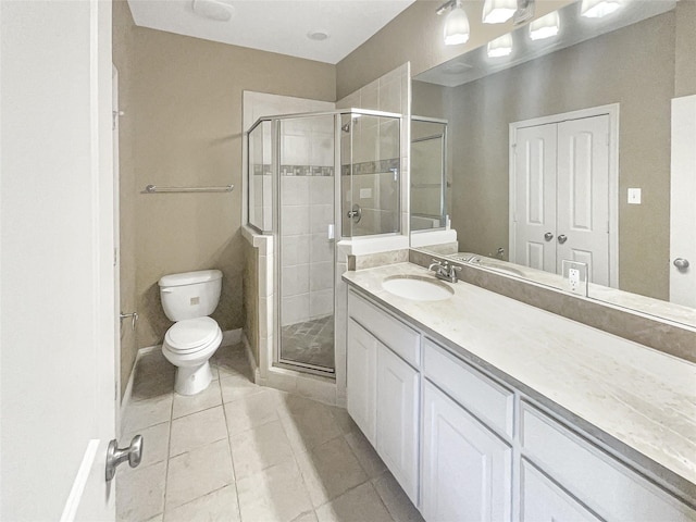 bathroom featuring toilet, vanity, tile patterned flooring, and a shower with shower door