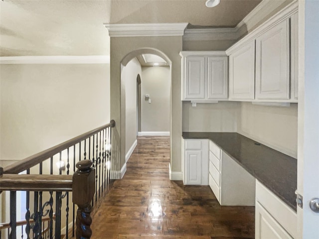 kitchen featuring dark wood-type flooring, ornamental molding, dark stone countertops, and white cabinetry