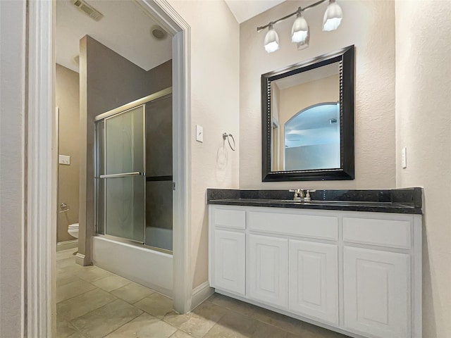 full bathroom featuring toilet, tile patterned flooring, vanity, and bath / shower combo with glass door