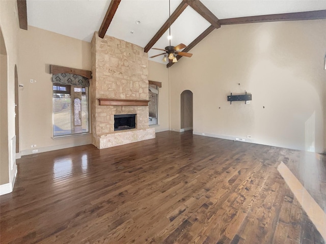 unfurnished living room with ceiling fan, dark wood-type flooring, high vaulted ceiling, a fireplace, and beam ceiling