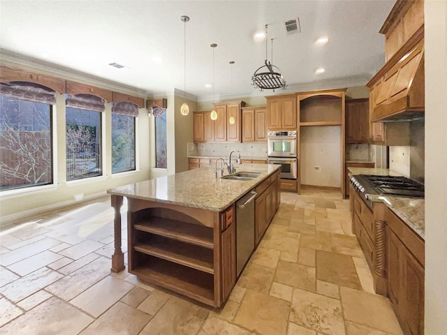 kitchen with light stone countertops, decorative light fixtures, a kitchen island with sink, appliances with stainless steel finishes, and sink