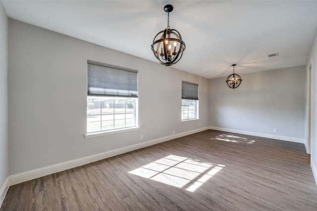 empty room with hardwood / wood-style flooring and a notable chandelier