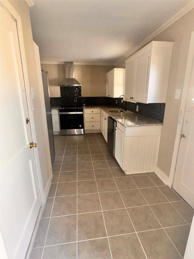 kitchen featuring appliances with stainless steel finishes, crown molding, wall chimney range hood, tile patterned flooring, and white cabinetry