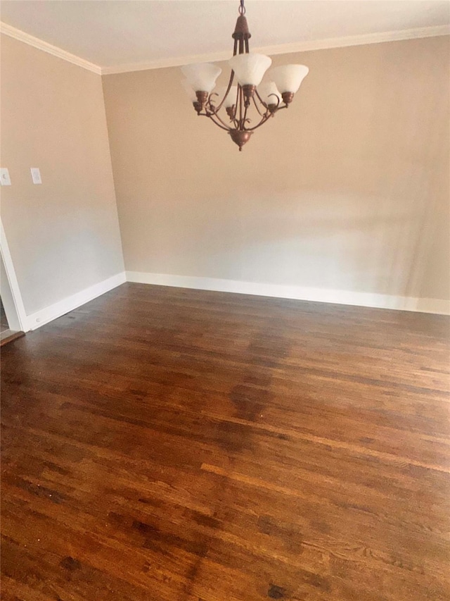 empty room with a chandelier, dark hardwood / wood-style floors, and ornamental molding