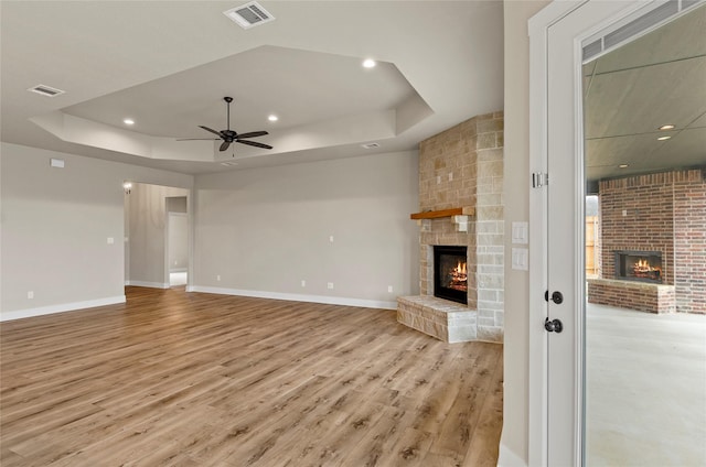unfurnished living room featuring visible vents, a raised ceiling, and a fireplace