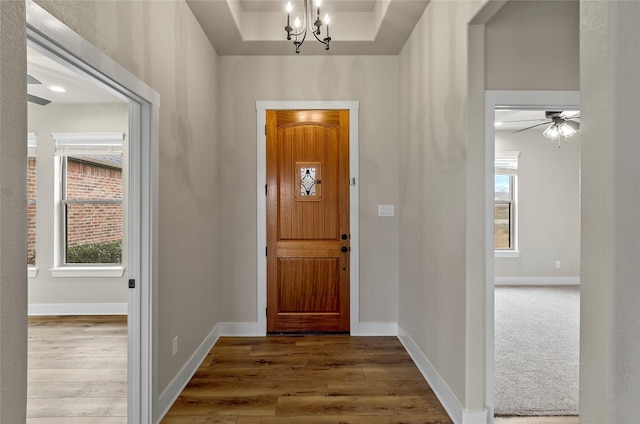 entryway featuring baseboards, wood finished floors, and a notable chandelier