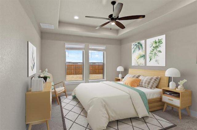 bedroom with a ceiling fan, visible vents, light colored carpet, a raised ceiling, and baseboards