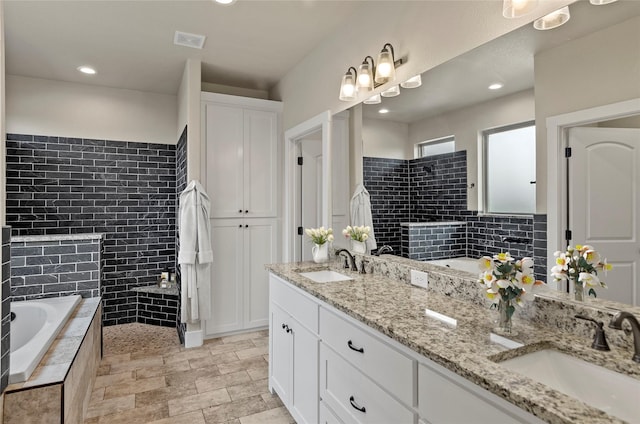 full bathroom featuring visible vents, a sink, a bath, and double vanity