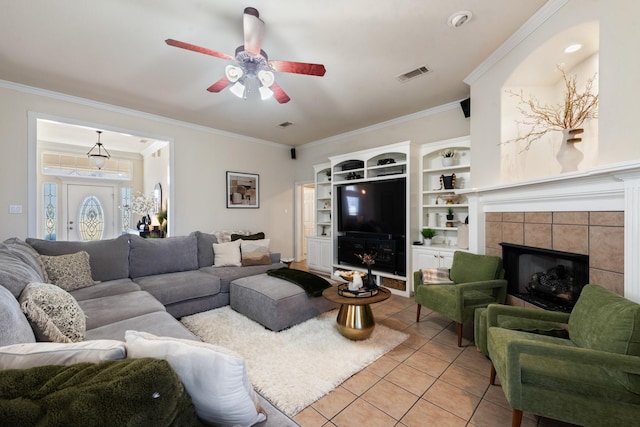 tiled living room with ceiling fan, crown molding, and a tiled fireplace