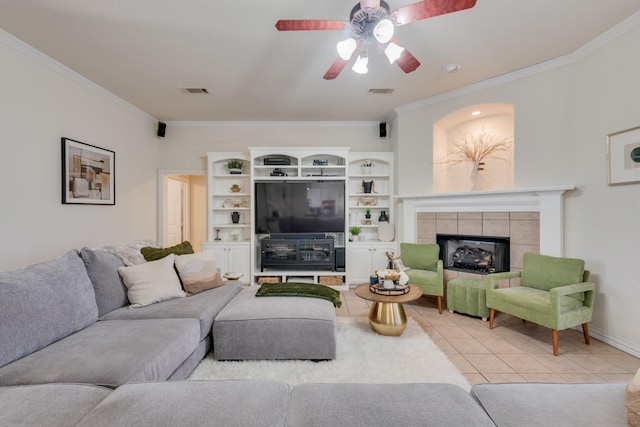 living room with ceiling fan, light tile patterned floors, crown molding, and a tile fireplace