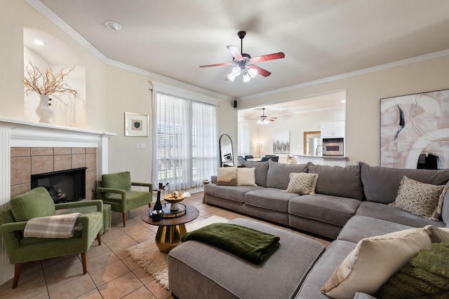 living room featuring ceiling fan, a fireplace, light tile patterned floors, and ornamental molding