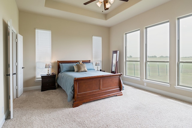 carpeted bedroom featuring ceiling fan and a raised ceiling