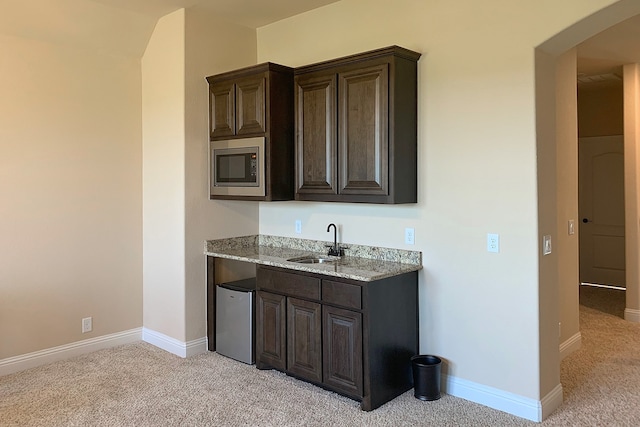 kitchen featuring sink, refrigerator, dark brown cabinets, stainless steel microwave, and light colored carpet