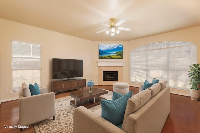 living room featuring hardwood / wood-style flooring, a tile fireplace, and ceiling fan