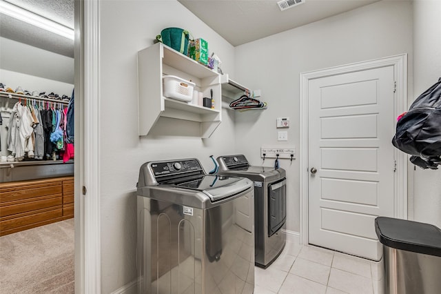 laundry area featuring washer and dryer, light tile patterned floors, and a textured ceiling