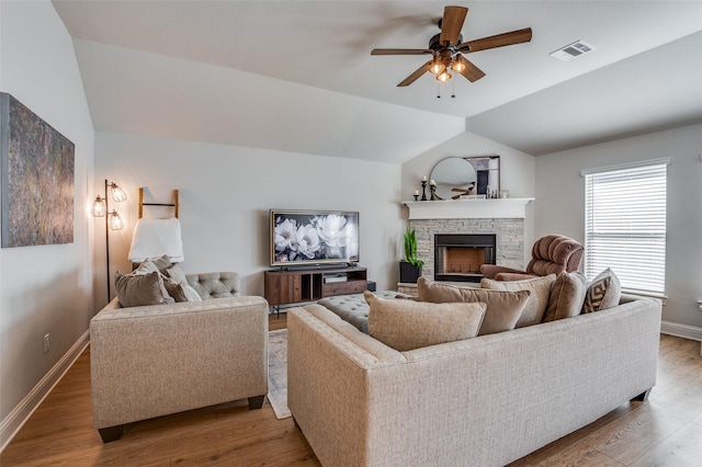 living room featuring hardwood / wood-style floors, ceiling fan, a fireplace, and vaulted ceiling