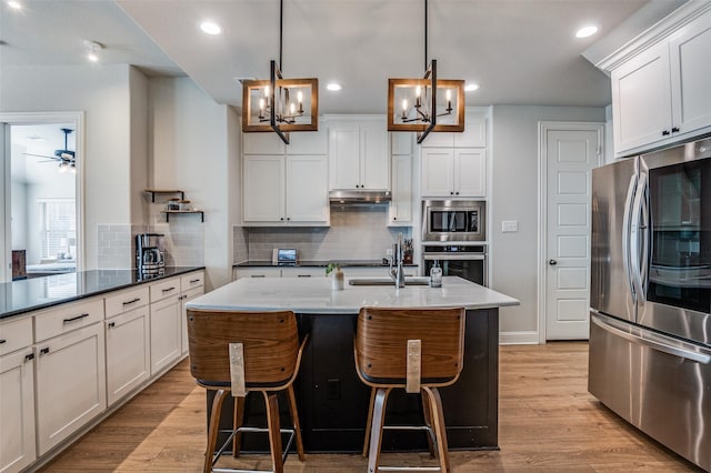 kitchen with pendant lighting, white cabinets, ceiling fan with notable chandelier, light hardwood / wood-style floors, and stainless steel appliances