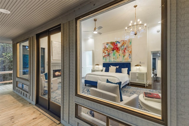 bedroom featuring ornamental molding, light wood-type flooring, a fireplace, and an inviting chandelier